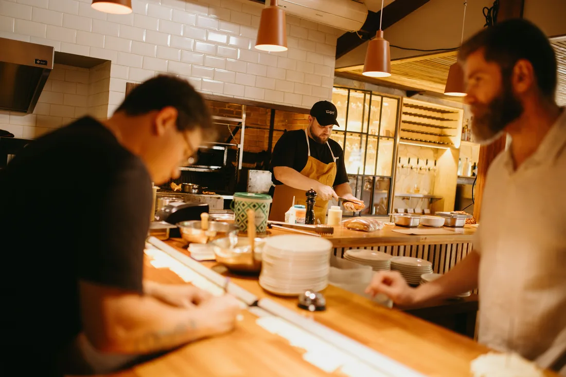 Equipo de cocina preparando y entregando platos durante el servicio de un restaurante